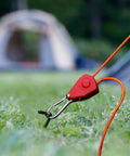 Stainless Steel Nylon Adjustable Rope Fastener With Fixed Buckle And Pulley for tent ropes, shown securing orange line on grass.