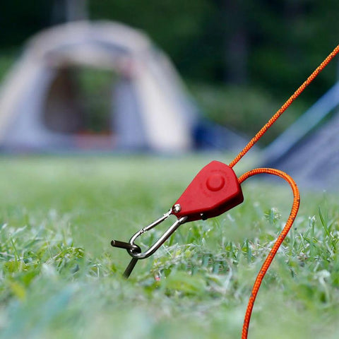 Stainless Steel Nylon Adjustable Rope Fastener With Fixed Buckle And Pulley for tent ropes, shown securing orange line on grass.