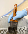 Person wearing Textured Blue Nitrile Gloves 5 Mil Powder Free Food Safe Large Box Of 100 holding a paintbrush over a paint can
