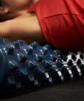 Person using 22-inch textured foam roller for deep tissue massage and self-myofascial release with firm, flexible bumps