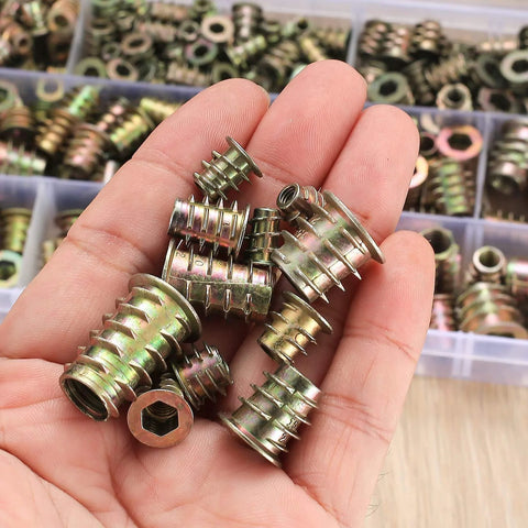 Close-up of a hand holding various sizes of zinc alloy threaded wood inserts from the 230 Piece Threaded Wood Inserts Set With 11 Sizes M4 M5 M6 M8 M10 Hex Socket Drive Furniture Fasteners.