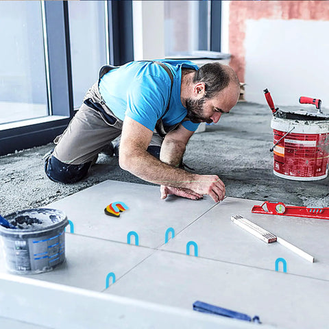 Person using 100 Piece Tile Spacer Set For Leveling Floors Windows And Toilets Horseshoe Plastic Shims in blue, red, yellow, black on tiles