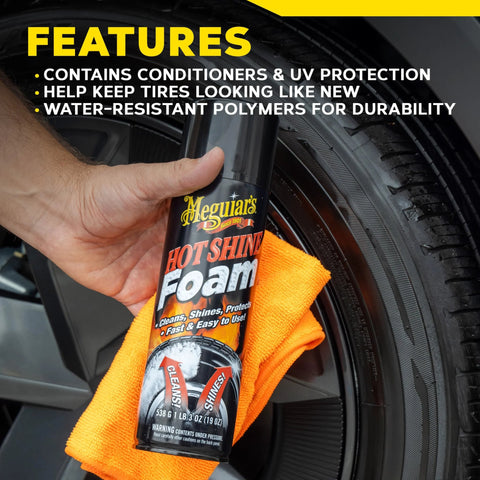Hand holding Hot Shine Tire Foam High Gloss Tire Shine That Cleans Shines And Protects In One Easy Spray Step For Deep Black Tire Finish With Conditioning Oils And UV Protection Stays Put Then Dissolves Clear Aerosol 19 Oz against a tire with an orange cloth.