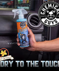 Hand holding 16 oz Tire Kicker Sprayable Extra Glossy Tire Shine Spray, restores wet look to rubber, vinyl, and plastic, dry to touch.