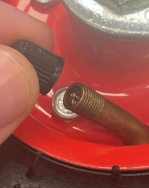 Close-up of a tire valve stem being capped, on a 4 Pack 6 Inch Swivel Pneumatic Air Caster Wheels With Knobby Tread For Industrial Carts.