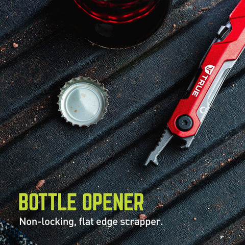 Close-up of ✝️ TRUE Titanium Block Multitool with bottle opener and red handle on textured surface next to open bottle cap.