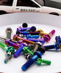 Colorful titanium bolts displayed in various colors with a background car model, aligned for showcasing design variety and appeal.