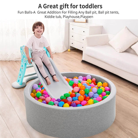 A child sliding into ball pit filled with Ball Pit Balls Pack of 100 - Phthalate Free BPA Free Crush Proof Plastic Ball, Play Balls for Ball Pit Pool Playpen Babies Kids Children Birthday Parties Pool Tent Party, in a living room.