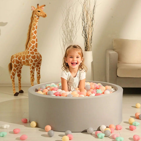 Child playing in gray ball pit with colorful star and heart shaped ball pit balls, giraffe decor in background. Ball Pit Balls,Plastics Balls for Ball Pit, Stars Hearts Shape for PastelBall for Toddlers Kids，6 Mix Colors,50pcs