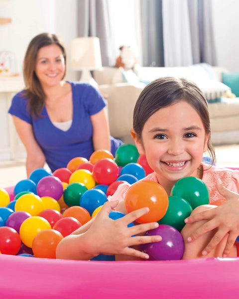 Child playing with Set of 100 Plastic Fun Balls for Ball Pits and Bounce Houses, Multi-Colored, surrounded by colorful balls in a playpen.
