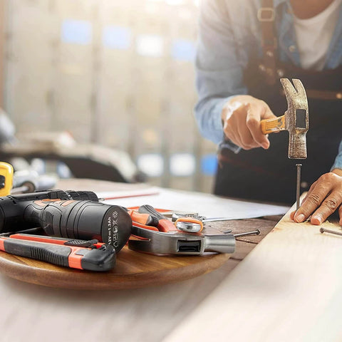 Person using a hammer on wood, with tools including a screwdriver on a lazy susan organizer surface.