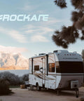 Recreational vehicle parked in a scenic area with mountains, trees, and a lake, featuring the Rockare logo.