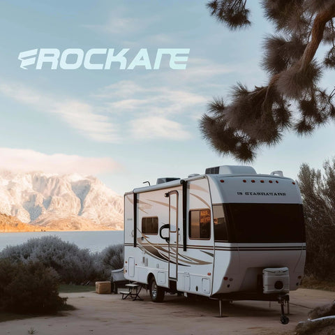 Recreational vehicle parked in a scenic area with mountains, trees, and a lake, featuring the Rockare logo.