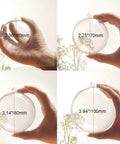 Four hands holding different sized transparent plastic balls labeled with dimensions, including a 3.14/80mm ball for DIY craft ornaments.