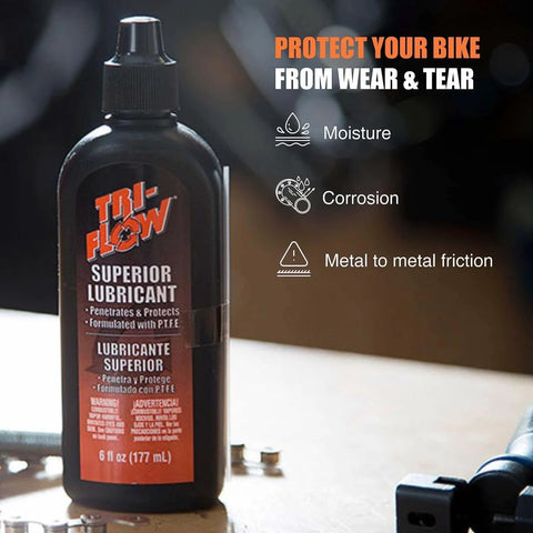 Tri-Flow Superior Lubricant bottle on workbench with moisture, corrosion, and metal to metal friction benefits listed