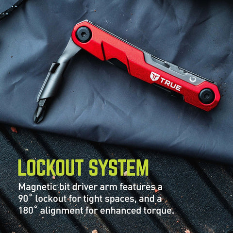 TRUE Titanium Block Multitool with a locking driver, folded, showing magnetic bit driver arm on dark fabric background.
