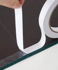 Two Rolls Of One Quarter Inch Six Millimeter Double Sided Adhesive Tape For Arts And Crafts Scrapbooking Card Making Gift Wrapping DIY Projects Photography And Office School Supplies Easy To Peel Yet Strong Hold And Removable By Hand being applied to a black surface.
