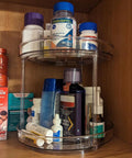 Two Tier Clear Lazy Susan Turntable Organizer With 360 Degree Rotation For Vanity And Bathroom Storage Spinning Makeup Skincare Perfume Holder Spice Rack And Cabinet Organizer For Kitchen Pantry holding medicine bottles and toiletries in a cabinet.
