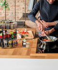 Two Tier Rotating Spice Organizer Turntable on kitchen counter with spices and sauces, showing height adjustable shelves