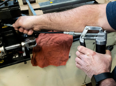 Hands using LubriMatic 30-800 Heavy Duty Mini Grease Gun w/ Pipe and Hose, Black/Silver, on machinery