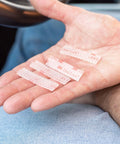 Hand holding clear dual-lock strips from Toll Tag Mounting Kit For EZ Pass I Pass SunPass With Alcohol Prep Pad Includes 8 Clear Double Sided Adhesive Strips And Velcro Strips Alien Tape Grip 4 Sets Install Easily For A Secure Tag Mount On Windshield Or Dash.