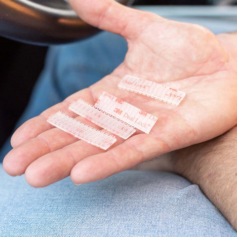 Hand holding clear dual-lock strips from Toll Tag Mounting Kit For EZ Pass I Pass SunPass With Alcohol Prep Pad Includes 8 Clear Double Sided Adhesive Strips And Velcro Strips Alien Tape Grip 4 Sets Install Easily For A Secure Tag Mount On Windshield Or Dash.