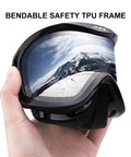 Hand holding ski goggles with silver lens showing mountain reflection, bendable safety TPU frame, ski goggles with ventilation anti fog system for men and women
