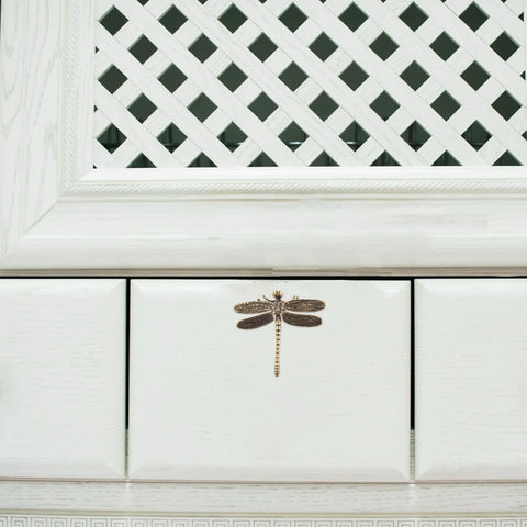 Front view of dragonfly cabinet knob with vintage brass finish on a white drawer, enhancing furniture aesthetic and home decor.