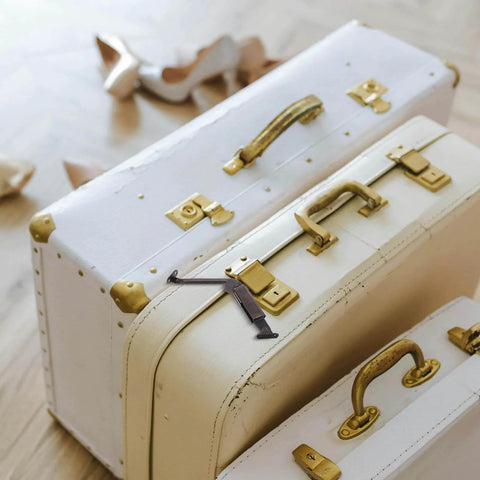Vintage white and beige suitcases with brass handles and clasps on wooden floor