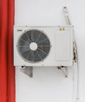 External air conditioning unit mounted on a wall with white and red surroundings