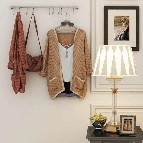 Wall with golden kitchen hanging racks, stainless steel rail holding 10 noiseless sliding hooks, featuring clothing instead of utensils.