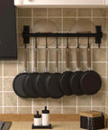 Kitchen Utensil Holder Hanger, Pot and Pan Rack Wall Mounted with 8 Hooks, Black, installed on tiled wall with frying pans hanging.