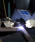 Person using Forty Pack Phos Copper Brazing Rods BCuP-2 with welding torch on metal, protective gear visible