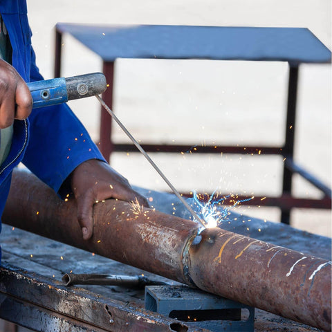 Person welding pipe with E308L-16 stainless steel rods for stainless and galvanized steel; AC and DC arc welding applications.