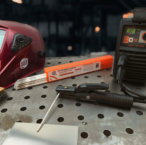 Aluminum E4043 Stick Electrode Rods for Welding, 1/8 Inch by 14 Inch, shown on metal table with welding helmet and machine