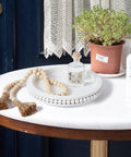 12 Inch White Beaded Lazy Susan Turntable for Tabletop and Countertop as kitchen tabletop centerpiece with beads, plant, and decor items.
