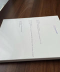 Closed white book on a wooden table with text and logo on the cover