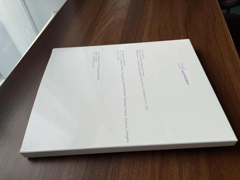 Closed white book on a wooden table with text and logo on the cover