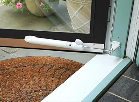 Heavy Duty Door Closer System (White) installed on a glass door with a patio view and brown doormat in the foreground.