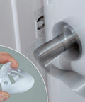 Door Silencer Strike Plate With Adhesive Bump Stops For Loud Doors No Drills Required Easy No Tools Install Flexible Noise Eliminating Solution That Stops Slamming Noises White Finish, shown installed on door with close-up of polymer body in hand.