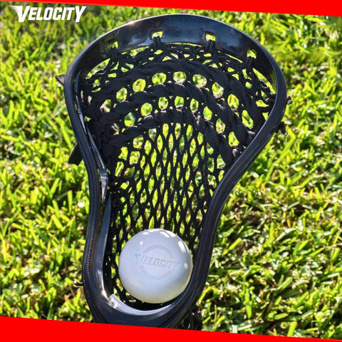 Cabeza de palo de lacrosse sosteniendo una pelota blanca sobre césped, con pelotas de lacrosse de práctica en paquetes de 1, 2, 3, 6, 12, 18, 24, 36, 60 y 120 unidades.