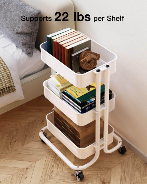 Three Tier Metal Rolling Utility Cart by Pipishell A Workhorse On Wheels With Two Lockable Wheels Great For Kitchen Dining Room And Living Room Storage And Organization Heavy Duty Mesh Shelves Mobile Serving Cart In White with books on tiers next to a couch.