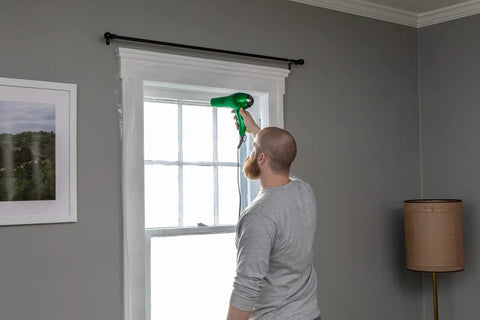 Person installing Window Insulation Kit With Rolled Shrink Film For Easy Indoor Installation Draft Blocking And Energy Savings.
