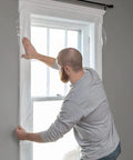 Person installing Window Insulation Kit With Rolled Shrink Film For Easy Indoor Installation Draft Blocking And Energy Savings