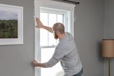 Person installing Window Insulation Kit With Rolled Shrink Film For Easy Indoor Installation Draft Blocking And Energy Savings