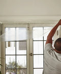Man installing Heavy Duty Window Insulation Kit For Cold Weather Fits Up To Five Windows With Puncture Resistant Shrink Film on window.