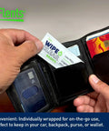 Person holding Wipe N Clear Basic Lens Wipes 100 Count Individually Wrapped for Travel in a wallet with credit cards.