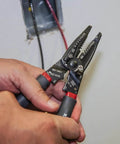 Person using Kurve Wire Stripper Crimper Cutter Multi Tool For 10-26 AWG Solid And 12-28 AWG Stranded Wire near a junction box.