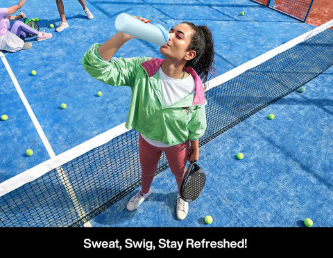 Woman drinking from a 26 oz insulated stainless steel water bottle with a 2‑in‑1 straw and spout lid on a tennis court