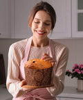 Smiling woman holding a panettone in a 48 Pack Easter Panettone Paper Mold 15 Oz Nonstick Brown Round Paska Kulich Baking Mold